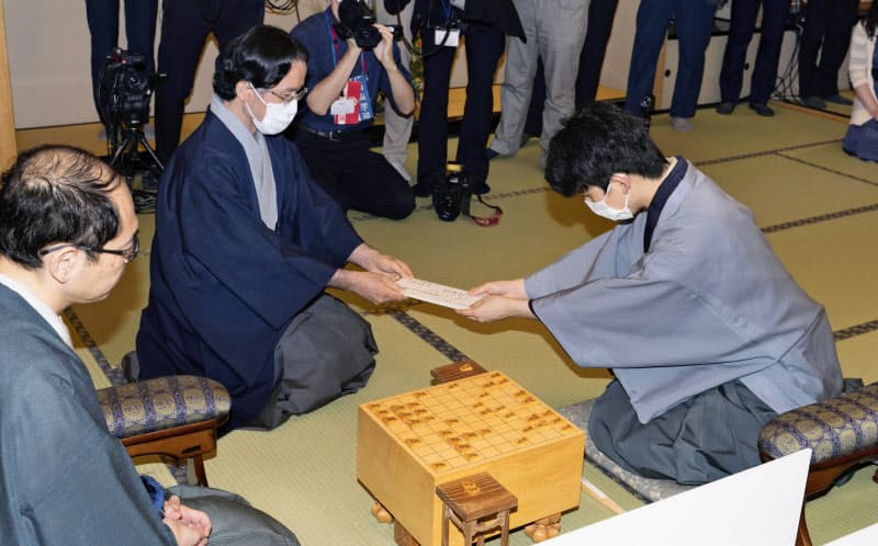 第61期王位戦7番勝負第2局の1日目を終え、封じ手を立会人(中央)に手渡す藤井聡太七段(当時)(7月、札幌市)=日本将棋連盟提供・共同 第61期王位戦7番勝負第2局の1日目を終え、封じ手を立会人(中央)に手渡す藤井聡太七段(当時)(7月、札幌市)=日本将棋連盟提供・共同
