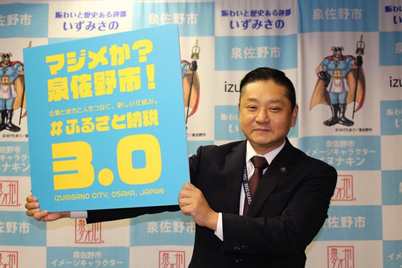 ふるさと納税の新しい仕組みの記者会見後、写真撮影に応じる千代松・泉佐野市長（30日、同市役所）