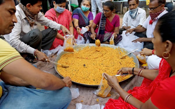 貧しい人々に届けるため食料を小分けするインドのボランティア。こうした最貧困層を支援する小グループの活動も政府規制の影響を受けそうだ=ロイター