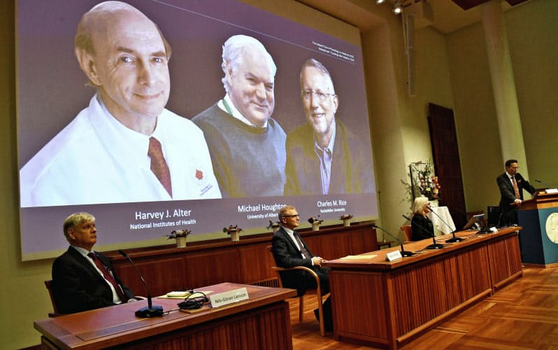 ノーベル生理学・医学賞の受賞が決まった(後ろの画面左から)アルター氏、ホートン氏、ライス氏を発表する記者会見(5日、ストックホルム)=ロイター ノーベル生理学・医学賞の受賞が決まった(後ろの画面左から)アルター氏、ホートン氏、ライス氏を発表する記者会見(5日、ストックホルム)=ロイター
