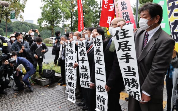 最高裁の判決を受け、紙を掲げる原告団(15日、最高裁前)