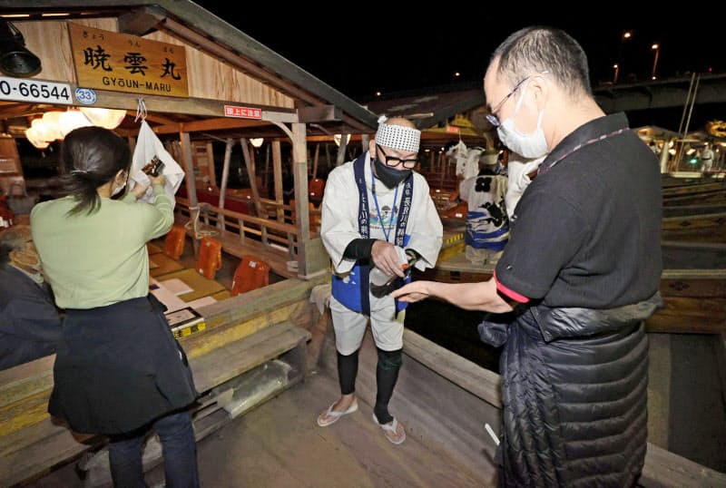 最終日を迎えた「長良川鵜飼」で、観覧船への乗船前に手を消毒する客(15日夜、岐阜市)=共同 最終日を迎えた「長良川鵜飼」で、観覧船への乗船前に手を消毒する客(15日夜、岐阜市)=共同