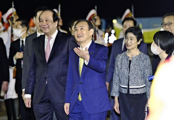 ハノイに到着し、真理子夫人(右)と共に出迎えを受ける菅首相(18日)=共同