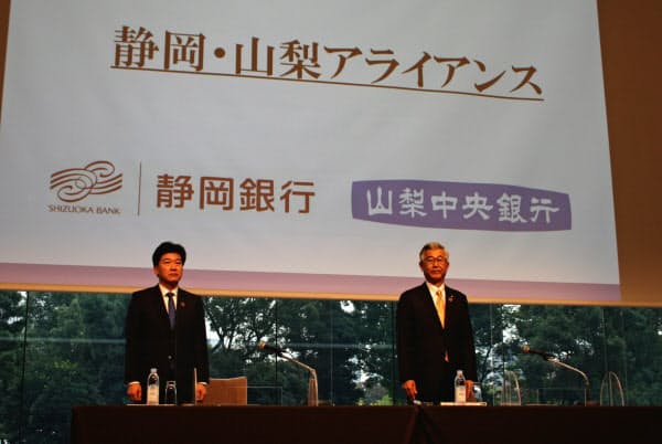 業務提携について発表する静岡銀行の柴田久頭取(左)と山梨中央銀行の関光良頭取(28日、東京・千代田のパレスホテル東京)