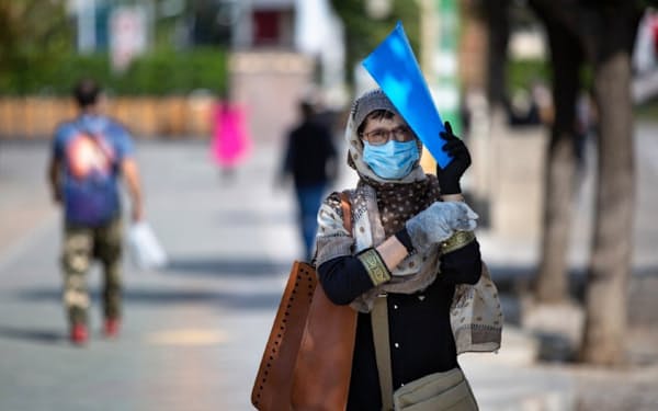 イランには感染「第3波」が到来(テヘランで手袋とマスク姿で歩く女性)
