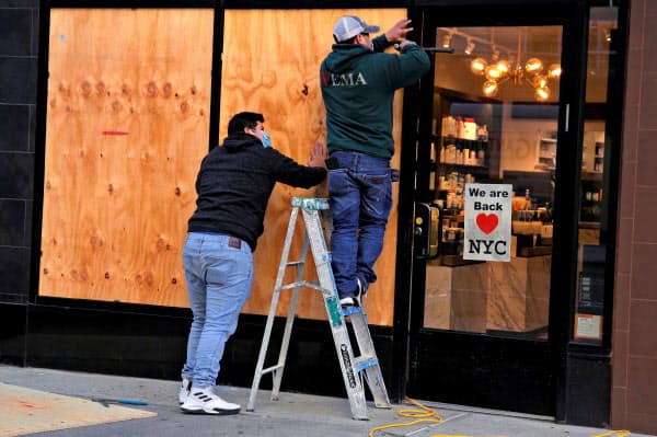 2日、ニューヨークで店舗のガラス窓をベニヤ板で覆う作業員=ロイター