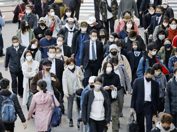 マスクを着用して歩く人たち。新型コロナウイルスの国内の新規感染者数が最多を更新した(12日、東京・新宿)=共同