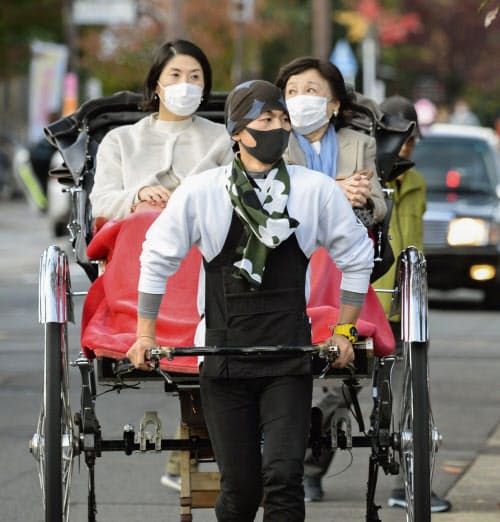 マスク姿で人力車に乗る人たち(12日、京都・嵐山)=共同