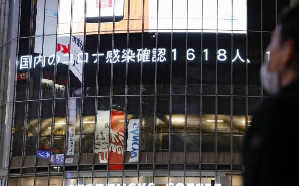国内の新たな新型コロナウイルス感染者数が1600人を超えたことを伝える東京・渋谷の大型ビジョン(12日夜)=共同