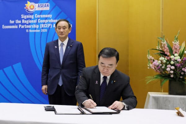 RCEPの協定に署名する梶山経産相(右)と首相(内閣広報室提供)