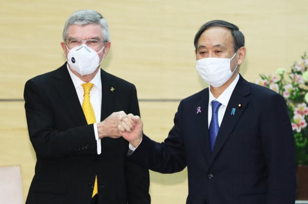 会談を前に拳を合わせる菅首相とIOCのバッハ会長(16日午前、首相官邸)