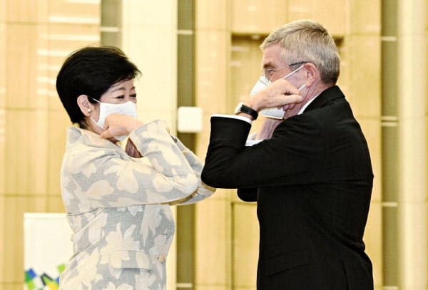IOCのバッハ会長(右)と肘タッチを交わす東京都の小池知事(16日、都庁)