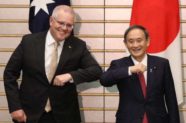 会談を前にオーストラリアのモリソン首相(左)と肘であいさつを交わす菅首相(17日、首相官邸)