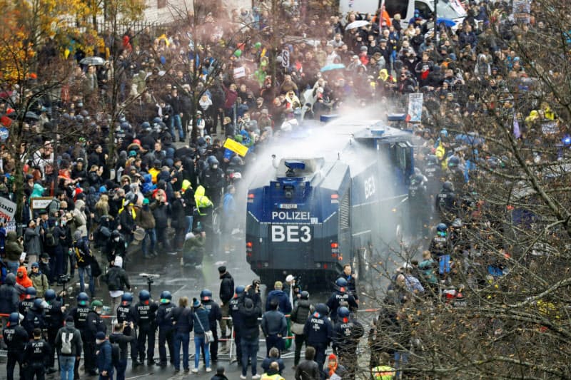 18日、ベルリンで、極右や市民らのデモに放水する警察車両=ロイター 18日、ベルリンで、極右や市民らのデモに放水する警察車両=ロイター