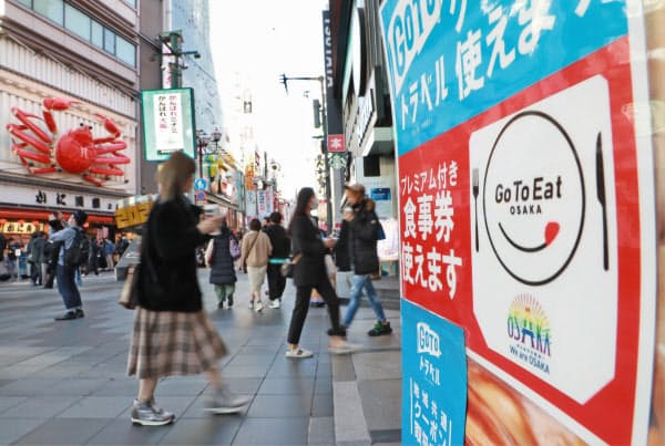 24日、西村経財相は大阪市、札幌市の除外について「できれば本日にも決定できるよう調整を急ぎたい」と述べた(写真は21日、大阪・道頓堀)