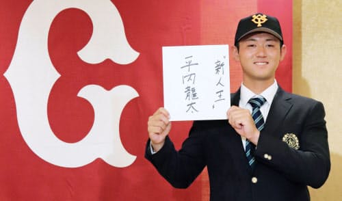 巨人にドラフト1位で入団することが決まり、「新人王」と書いた色紙を手に笑顔の平内龍太投手(23日、東京都内のホテル)=共同
