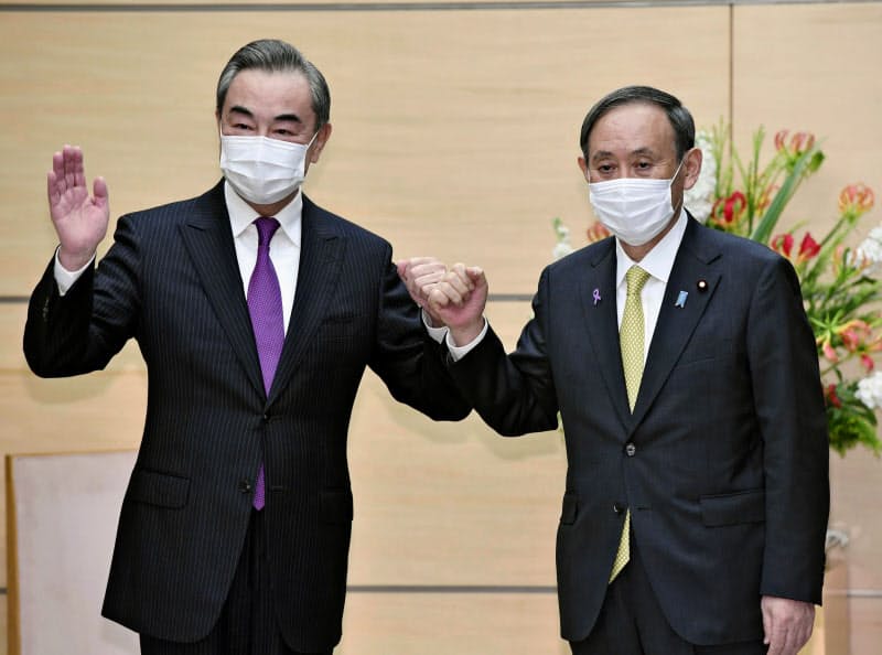 会談前、グータッチを交わす中国の王毅国務委員兼外相(左)と菅首相=25日午後、首相官邸 会談前、グータッチを交わす中国の王毅国務委員兼外相(左)と菅首相=25日午後、首相官邸