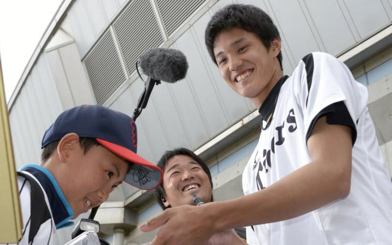 サインはファンと選手をつなぐ大切なものだ(2013年2月、春季キャンプで男の子にサインを手渡す阪神・藤浪)=共同 サインはファンと選手をつなぐ大切なものだ(2013年2月、春季キャンプで男の子にサインを手渡す阪神・藤浪)=共同