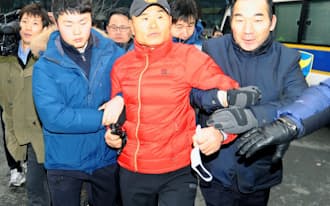 22日、ソウルの日本大使館に物を投げ込もうとして警察官に連行される男（中央）=共同