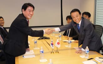 米ワシントンでの会談前に握手する麻生財務相（右）と韓国の崔経済副首相=財務省提供・共同