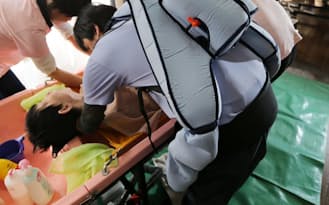 「マッスルスーツ」を装着して高齢者の入浴を手助けする介護スタッフ（川崎市）