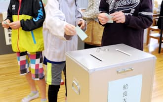 実際の投票箱などを使い模擬投票を行う小学6年生（6日、東京都多摩市の多摩第一小学校）