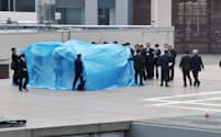 首相官邸の屋上で見つかった無人小型機・ドローンを調べる捜査員ら（22日、東京・永田町）