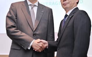 記者会見で握手するサントリー食品インターナショナルの鳥井社長(左)とJTの大久保副社長（25日午後、東京都千代田区）