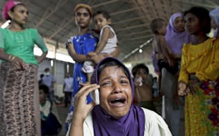 　インドネシア・アチェ州の避難所で、泣きながら親族と携帯電話で話すロヒンギャの難民（ロイター=共同）