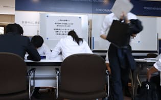 新卒採用の選考会場で受付用紙に記入する学生（1日午後、東京都渋谷区）