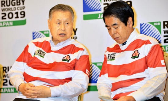 ラグビーW杯日本大会開催に暗雲が広がっている（7月15日、「キックオフミーティング」で下村文科相（右）と話す森元首相）=共同