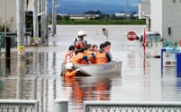 渋井川（奥）の堤防が決壊し、浸水した住宅地からボートで救助される住民ら（11日午前、宮城県大崎市）