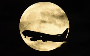 通常より大きく見える満月「スーパームーン」の前を横切る旅客機（28日午後、大阪市中央区より望む）=写真　浦田晃之介