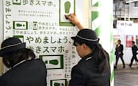 JR新宿駅に張られる、歩きながらスマートフォンや携帯電話を使うのをやめるよう呼び掛けるポスター（11月2日）=共同