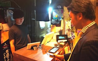 居酒屋「和食Dining　黒田」（東京都新宿区）での生体認証決済の様子。センサーに指を押しつけるだけで決済が完了する。30歳前後男性の利用が多いという