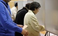 大阪ダブル選で、投票用紙に記入する有権者（22日午前、大阪市福島区）=共同