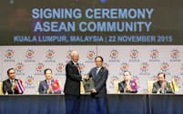クアラルンプールで行われた「ASEAN共同体」の発足式典で握手するマレーシアのナジブ首相（手前左）とASEANのレ・ルオン・ミン事務局長（22日）=共同