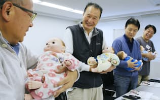 人形を使って赤ちゃんの抱き方などを学ぶシニア男性（東京都千代田区）