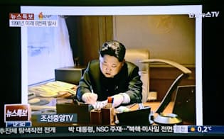 朝鮮中央テレビの「特別重大報道」で放映された、ミサイル発射に関する文書に署名する金正恩第1書記（聯合ニューステレビから）=共同
