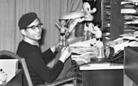 仕事場で鉄腕アトムの人形を手にする手塚治虫さん（1963年5月）=共同
