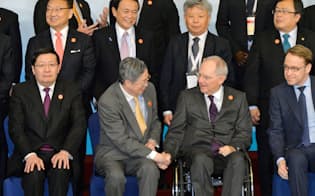 G20財務相・中央銀行総裁会議の記念撮影を前に、握手を交わすドイツのショイブレ財務相（前列右から2人目）と中国人民銀行の周小川総裁（同3人目）。後列左から2人目は麻生財務相（27日、中国・上海）=共同