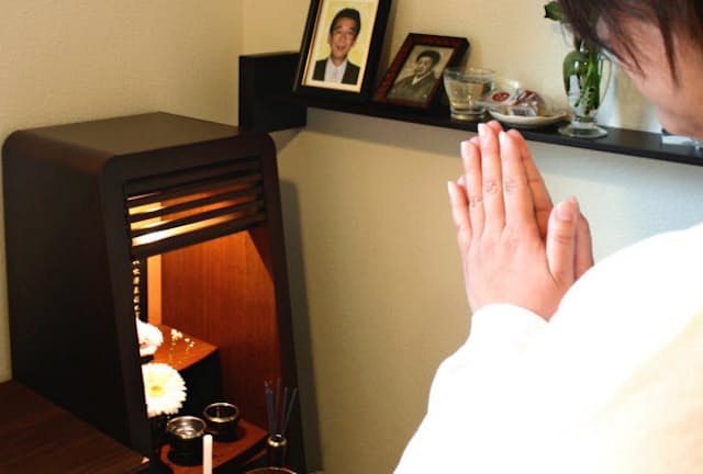 父の位牌に手を合わせる佐藤好美さん。父が最期を過ごした部屋に小さな仏壇を置いた
