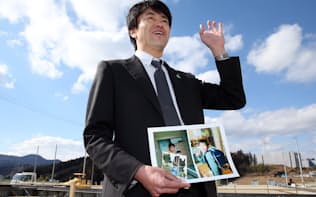 高台に再建中の自宅前で、亡くなった次男・祐太君の写真を手にする村上さん（2016年2月）