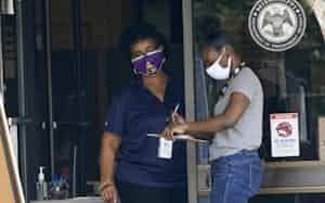 提出書類の記入を手伝う雇用安定所職員(米ミシシッピ州)=AP 提出書類の記入を手伝う雇用安定所職員(米ミシシッピ州)=AP