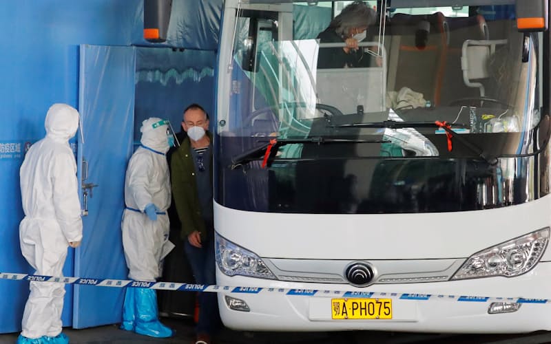 飛行機で湖北省武漢市に到着後、空港でバスに乗り込むWHOの調査団(14日)=ロイター 飛行機で湖北省武漢市に到着後、空港でバスに乗り込むWHOの調査団(14日)=ロイター