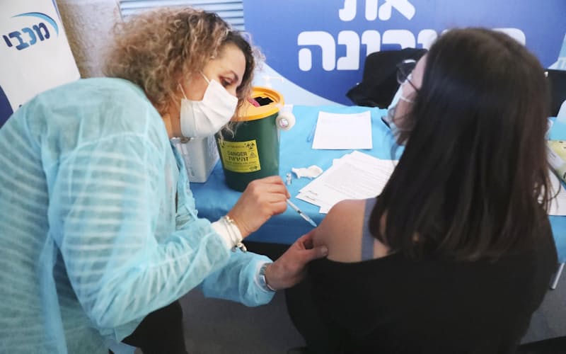 5日、エルサレムで新型コロナウイルスのワクチンを接種する看護師(左)=共同 5日、エルサレムで新型コロナウイルスのワクチンを接種する看護師(左)=共同