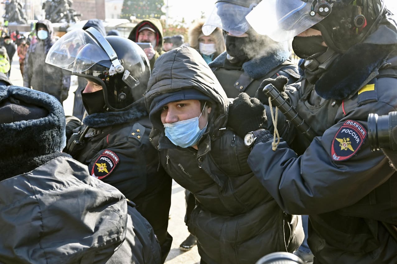 31日、ウラジオストク中心部で抗議デモ参加者とみなされ、警察官に拘束される男性=共同