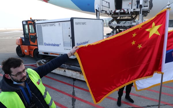 1月16日、中国製コロナワクチンがセルビアに到着、ベオグラードの空港で中国国旗を掲げる男性=ロイター