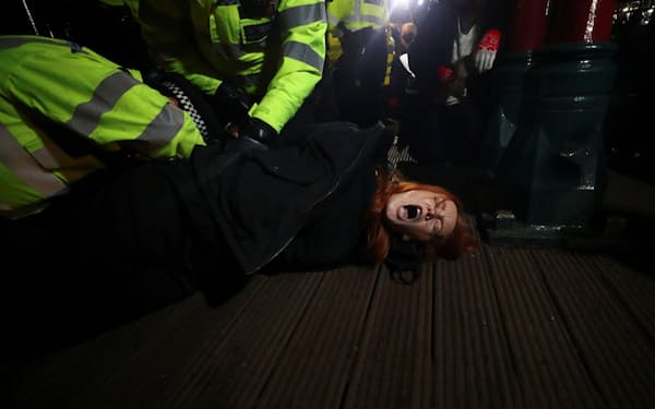 殺害された女性の追悼集会で参加者を押さえつける警察官（13日、ロンドン）=ロイター