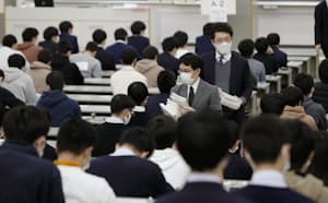 大学入学共通テストの問題用紙を配る試験官(1月、兵庫県西宮市の関西学院大)=共同 大学入学共通テストの問題用紙を配る試験官(1月、兵庫県西宮市の関西学院大)=共同